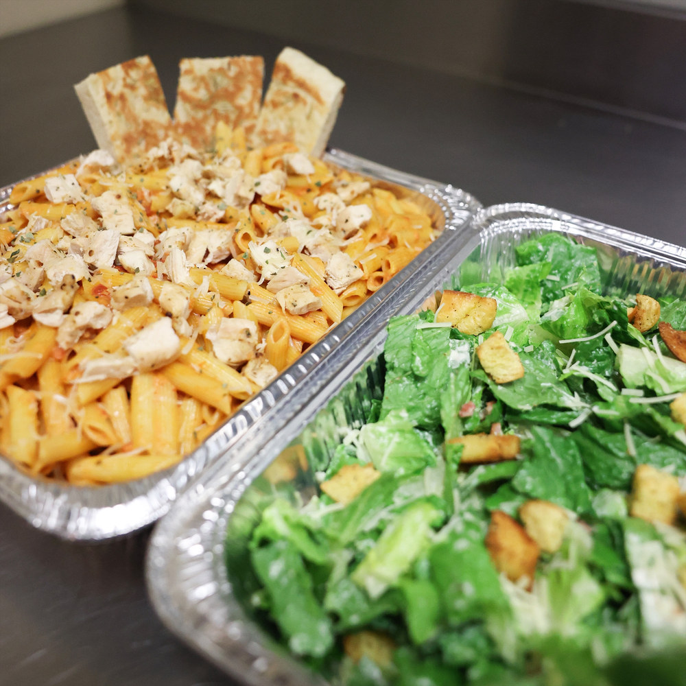 Chicken penne and Caesar salad in catering trays