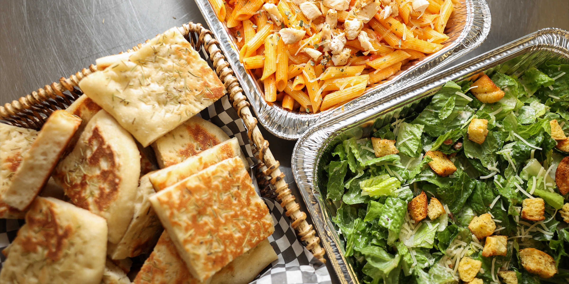 A Sixteen Mile Catering spread of flatbread, pasta and Caesar salad